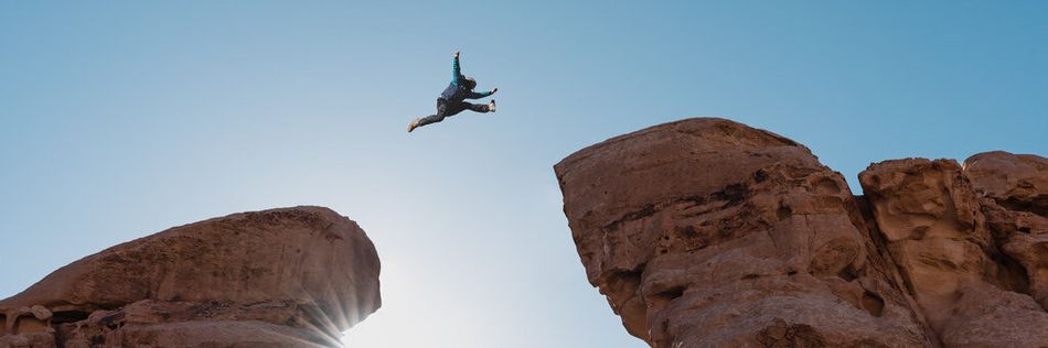 Ein Mensch springt über eine Felsenschlucht