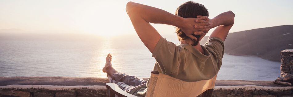 Ein junger Mann sitzt am Strand und blickt auf das Meer